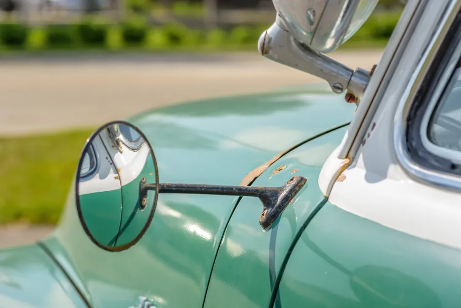 Chrome side mirror on a mint green classic car
