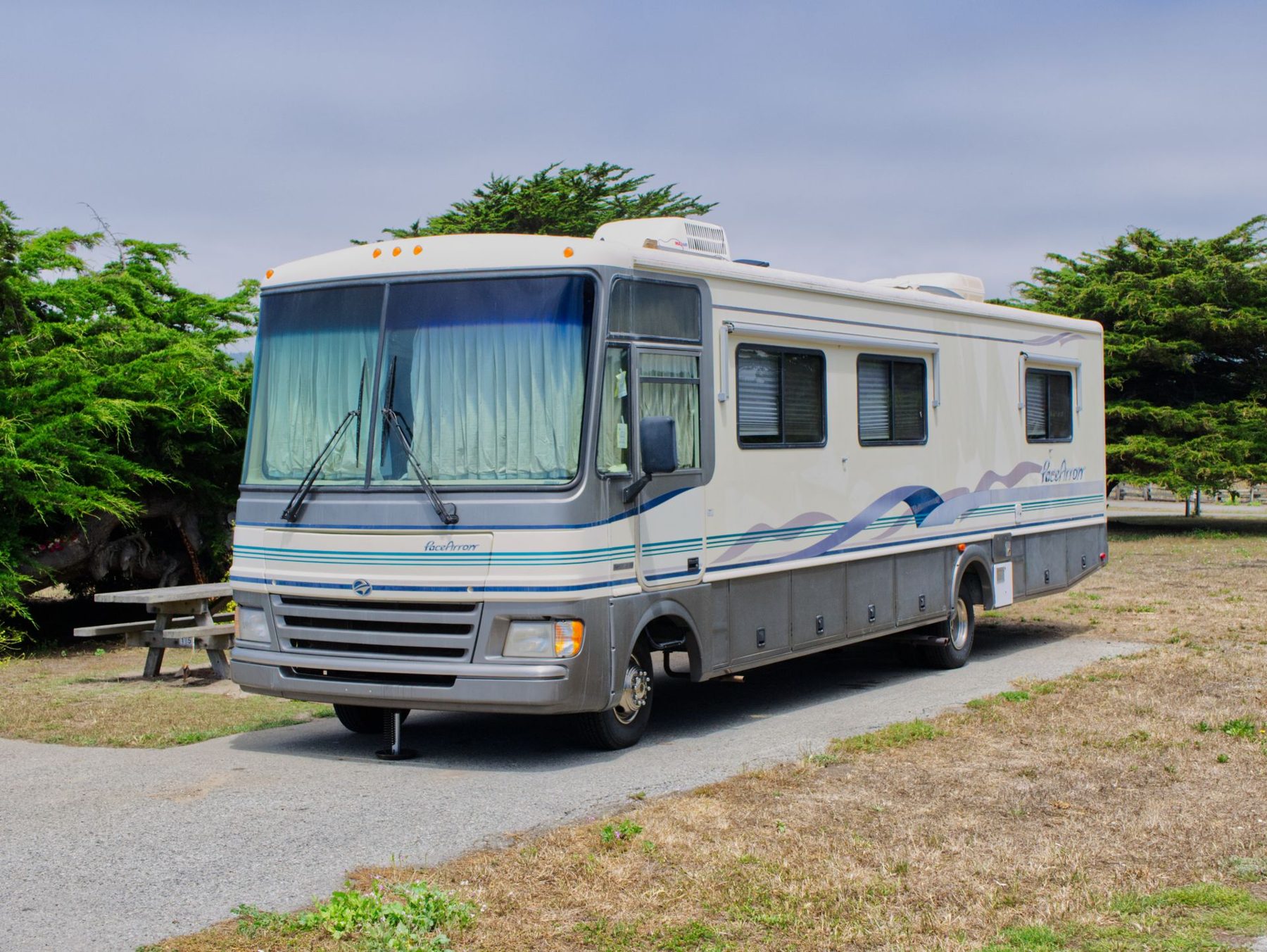 Class A motorhome parked beside trees