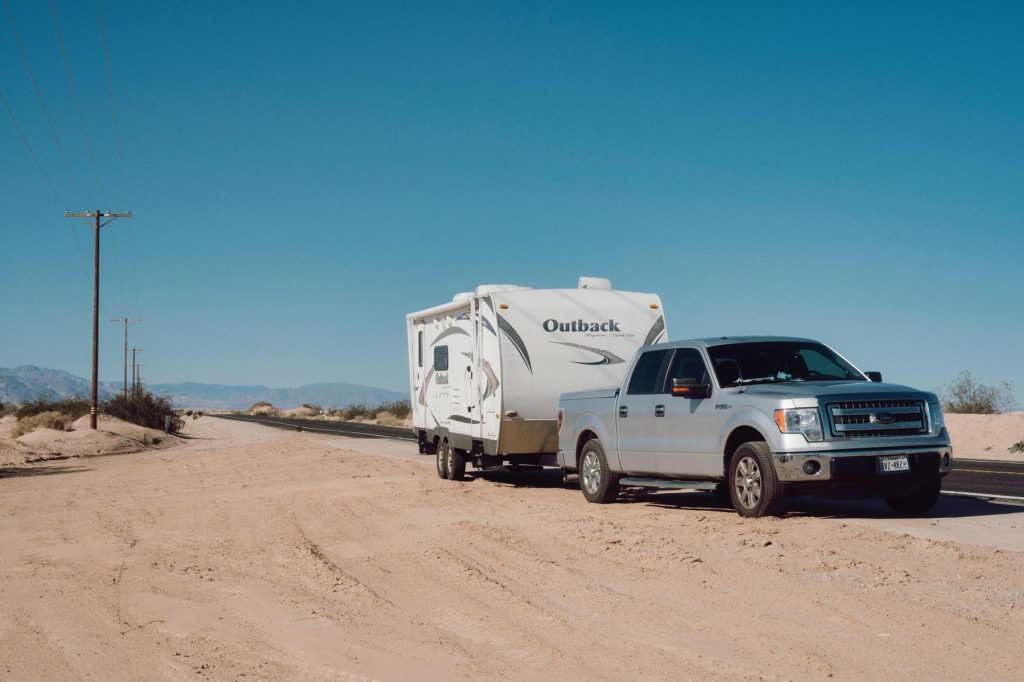 Pickup truck towing a travel trailer under a blue sky